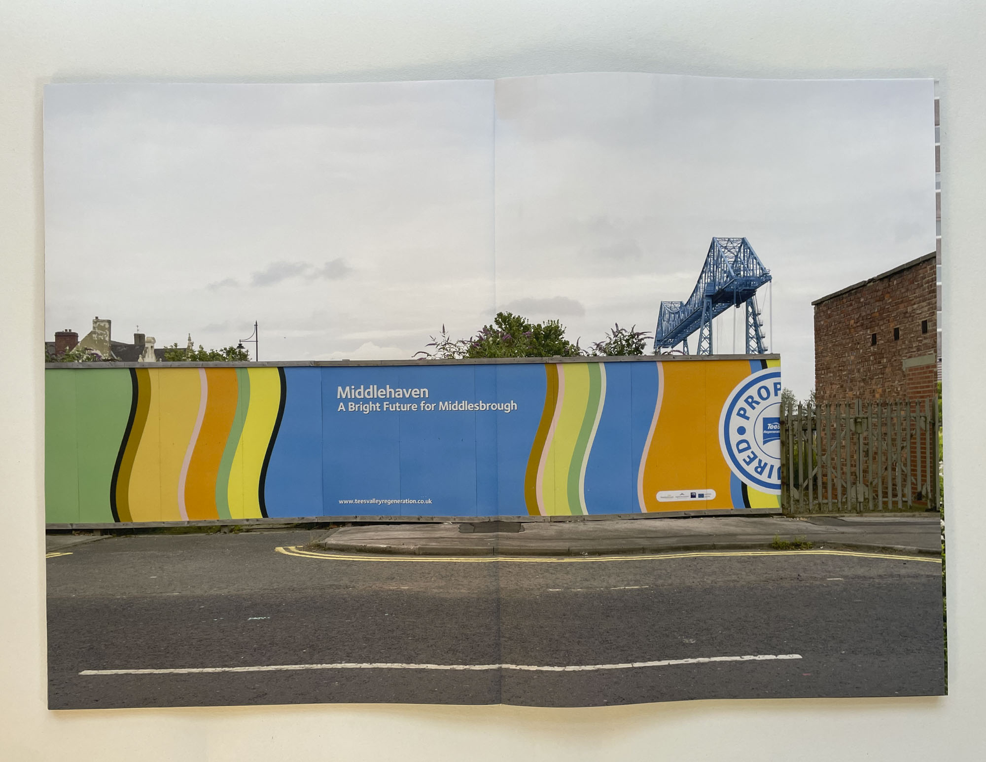 a hoarding displays the words Middlehaven - a Bright future for Middlesbrough, behind rises the towns transporter