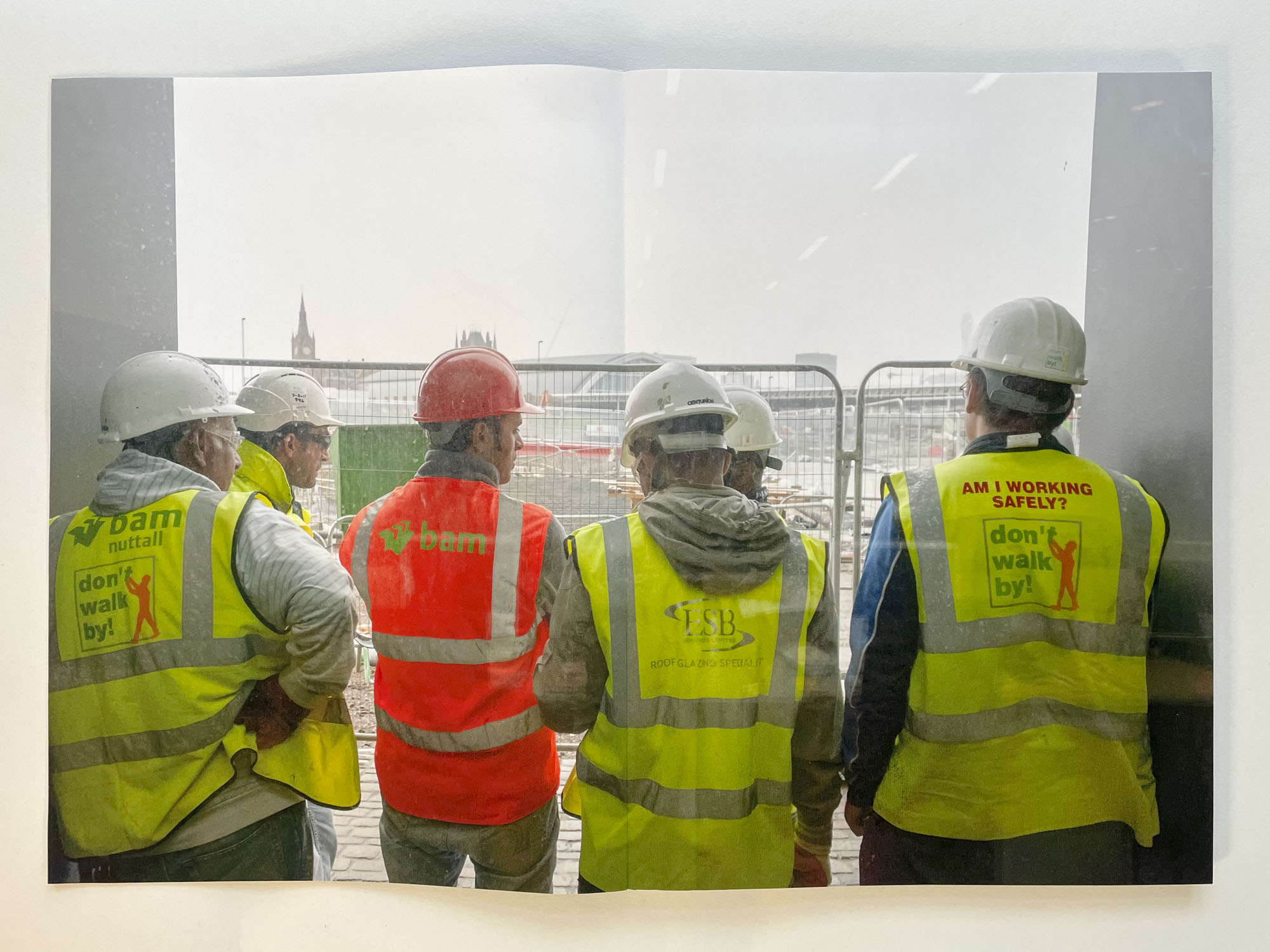a photograph shows a group of builders in hard hats looking at a building site at Kings Cross