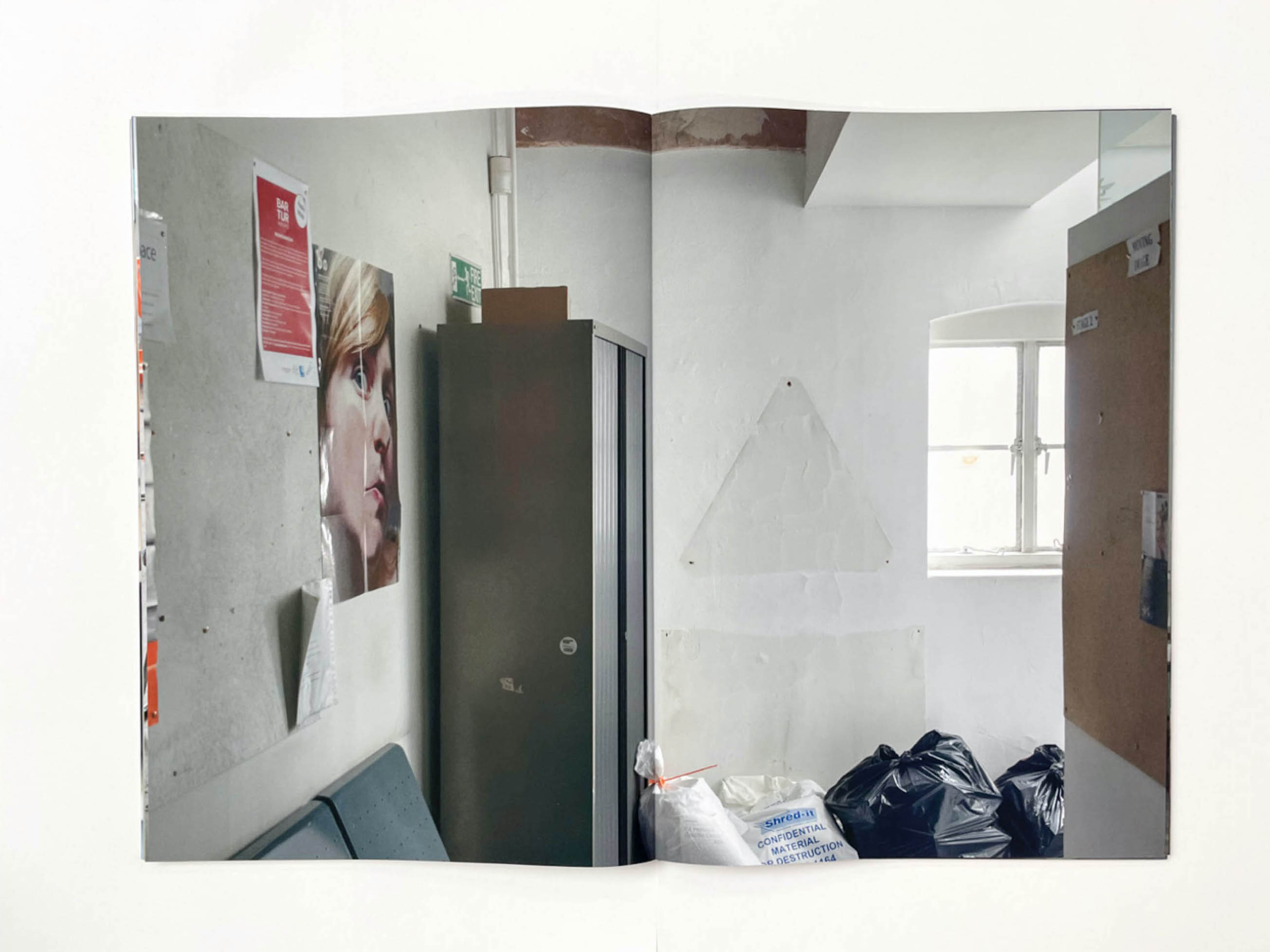 the corner of a corridor with plastic bin bags, on the wall a poster shows a womans face squashed against glass