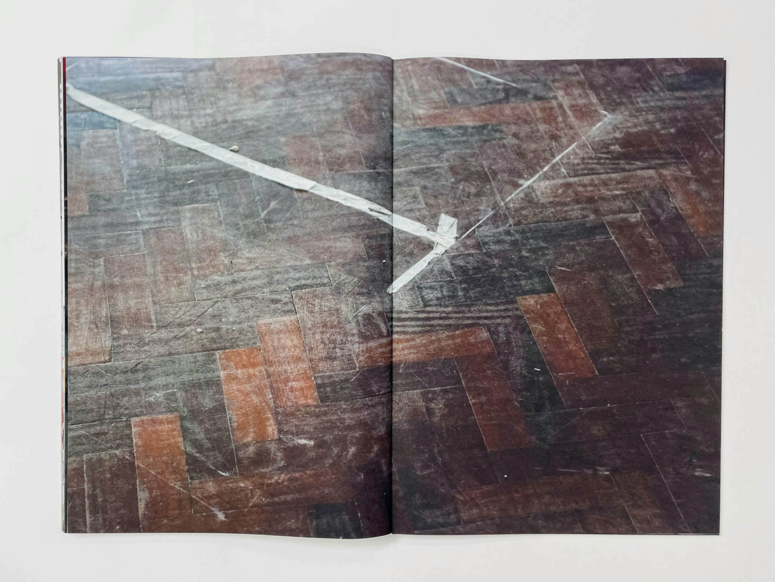 a dusty parquet floor with a rectangle traced by masking tape