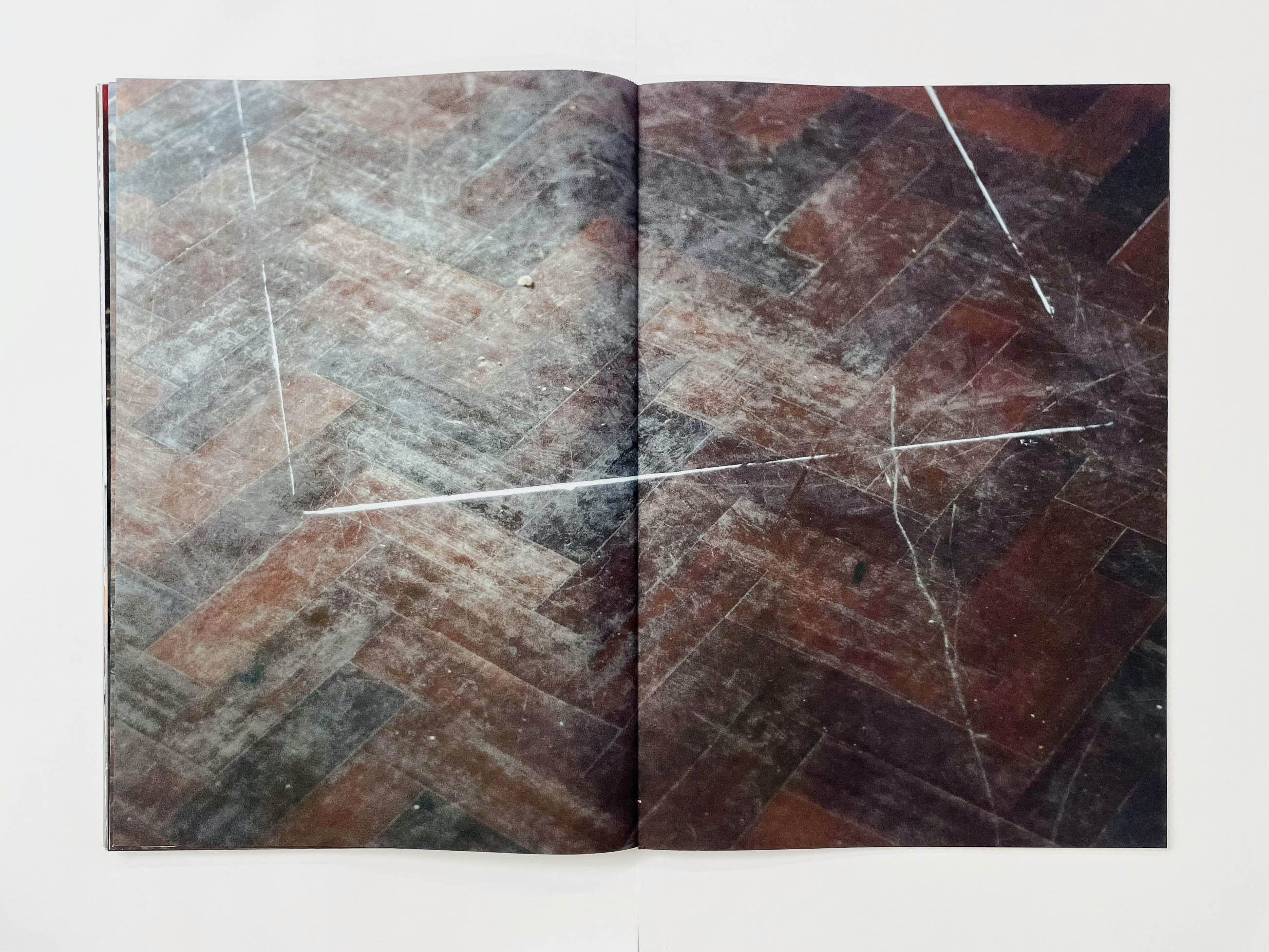 a dusty and scratched parquet floor with a different rectangle traced by tape