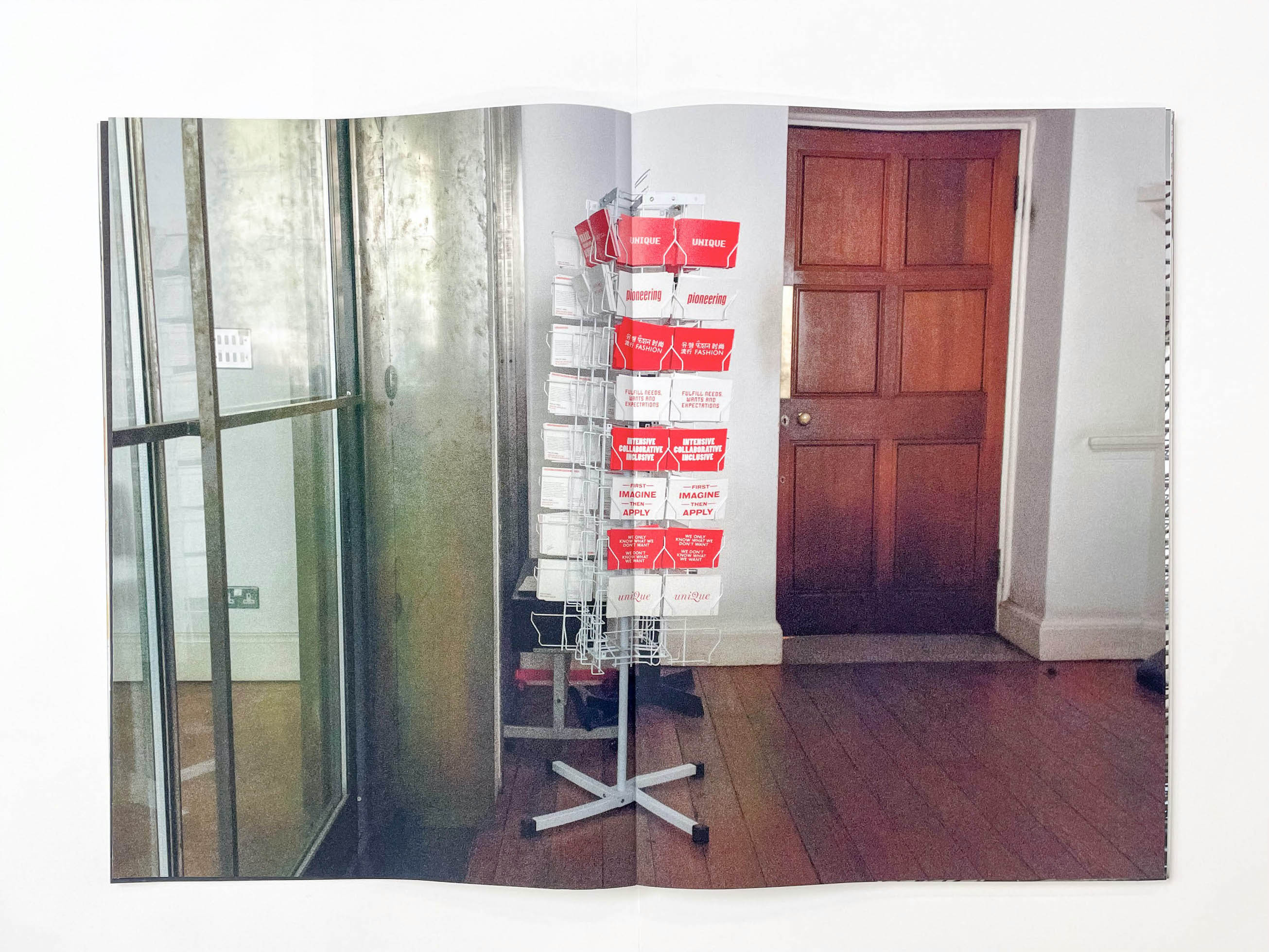 a wire stand holds promotional postcards for the college printed in red and white