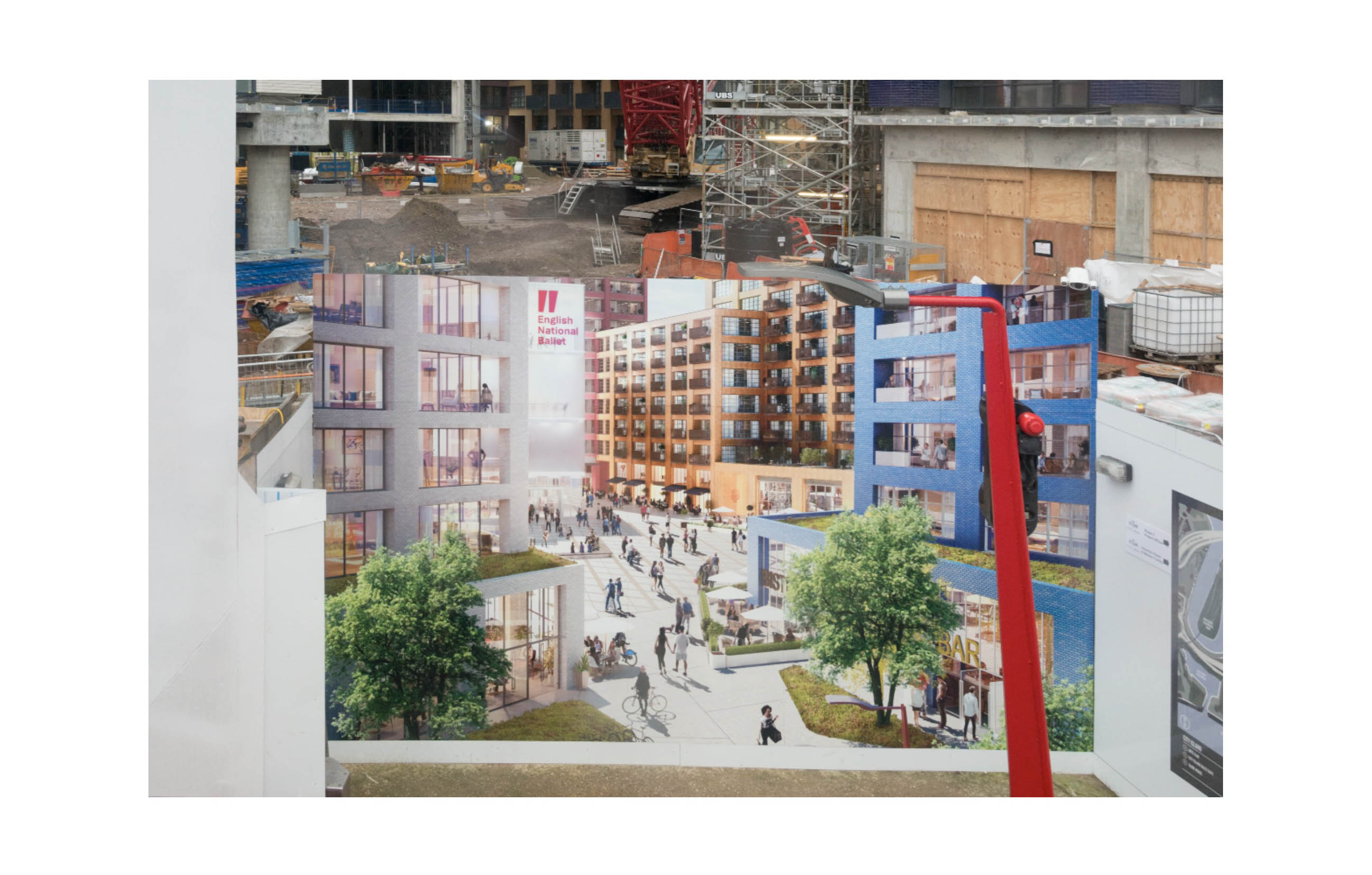 a hoarding shows a planned square with people in a new development, beyond the hoarding lies a chaotic building site