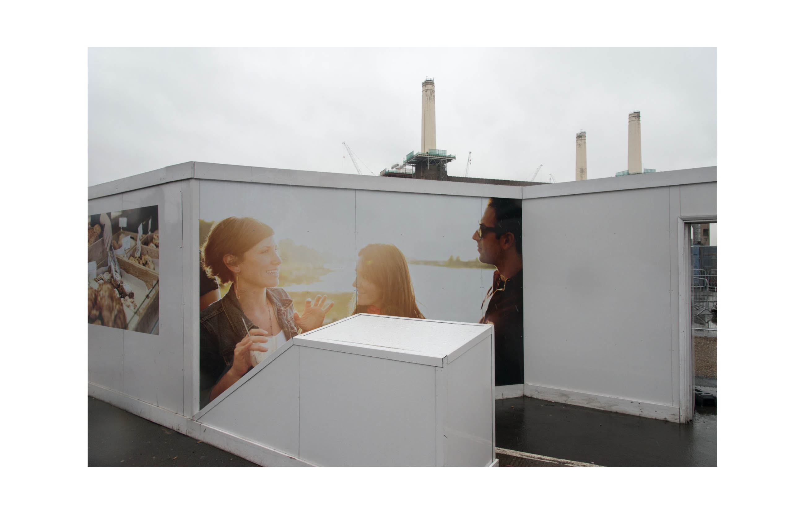A hoarding is illustrated with white people discussing something against a sunset, behind the hoarding Battersea Power Station can be seen