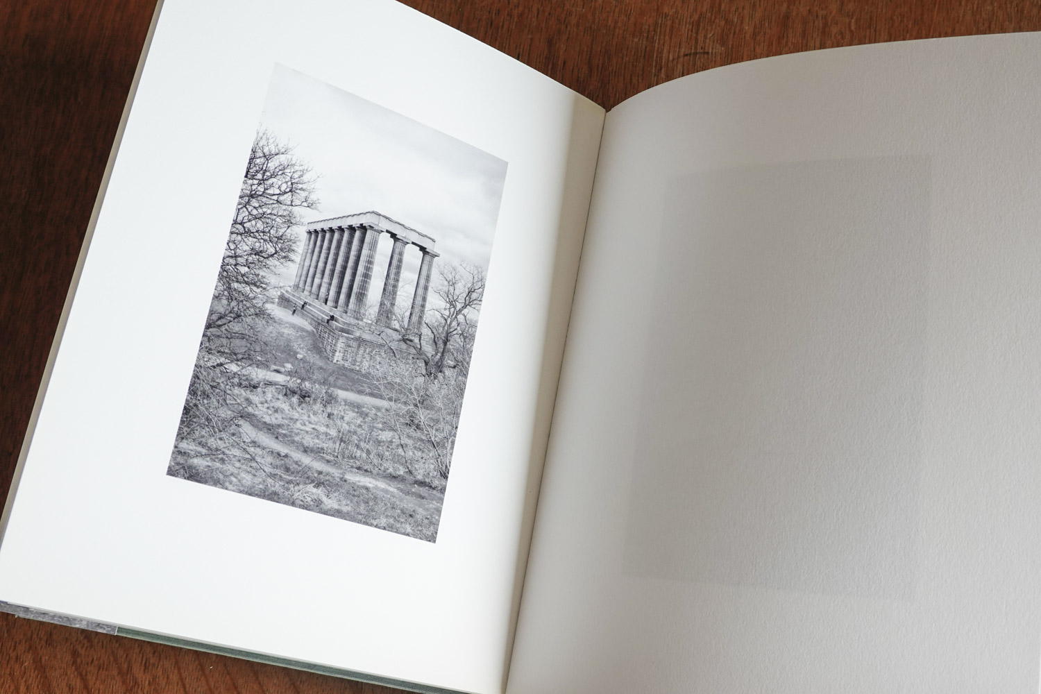 Photo of the book Oneiric open at a page showing a black and white photograph of a classical folly in a park.