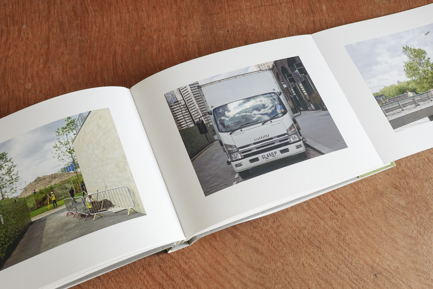 the open book displays three photos, the scene with the surveyor, a parked white van whose windscreen reflects a cloudy sky and the last photo is seen partially showing the edge of a bridge