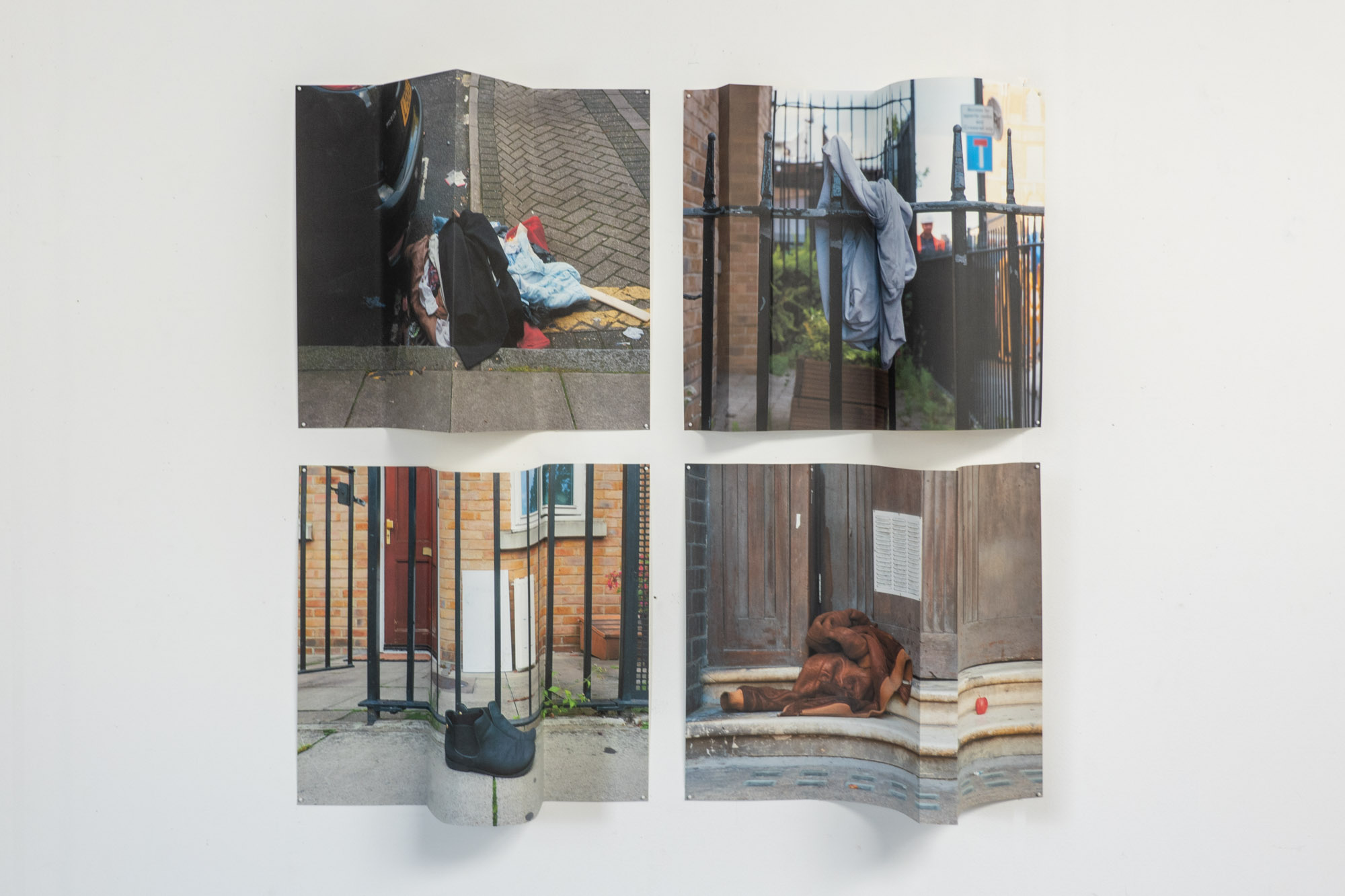 four prints of discarded clothing pinned on a wall in a rectangular grid