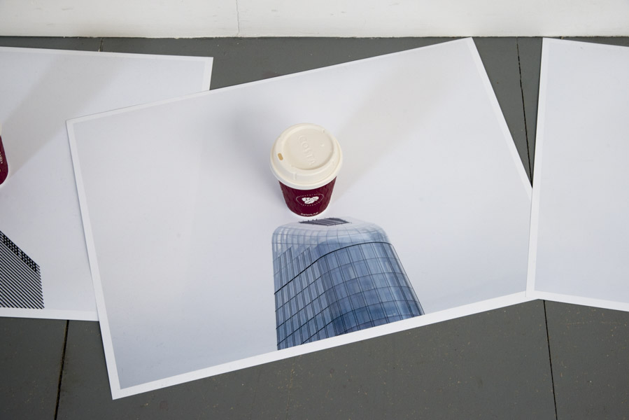 a close-up view of the second print on glossy paper of the top of a skyscraper, in the centre of which is a Costa coffee cup