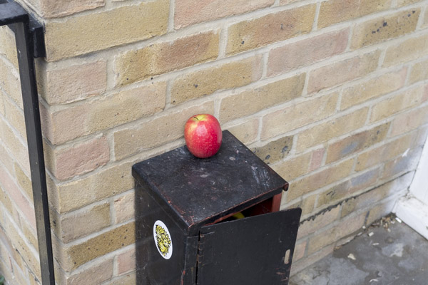 a red apple sits on top of a black metal box in the doorway