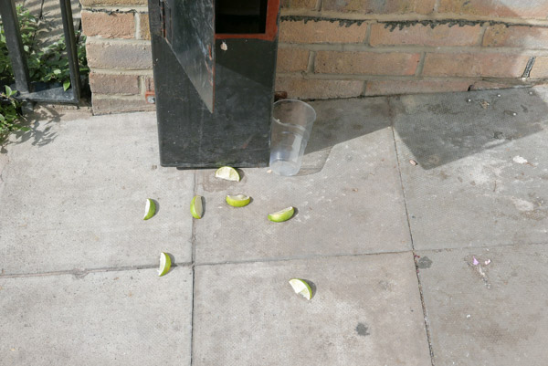 seven slices of lime lie discarded by an empty plastic cup in the doorway